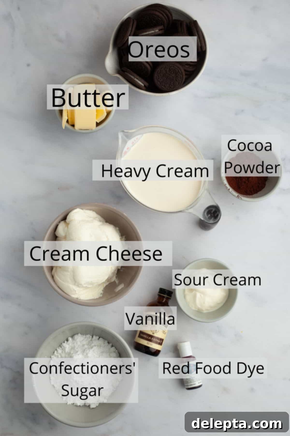 Decadent No-Bake Red Velvet Oreo Cheesecake 3 A collection of ingredients for red velvet oreo cheesecake, meticulously measured into small bowls on a kitchen counter.