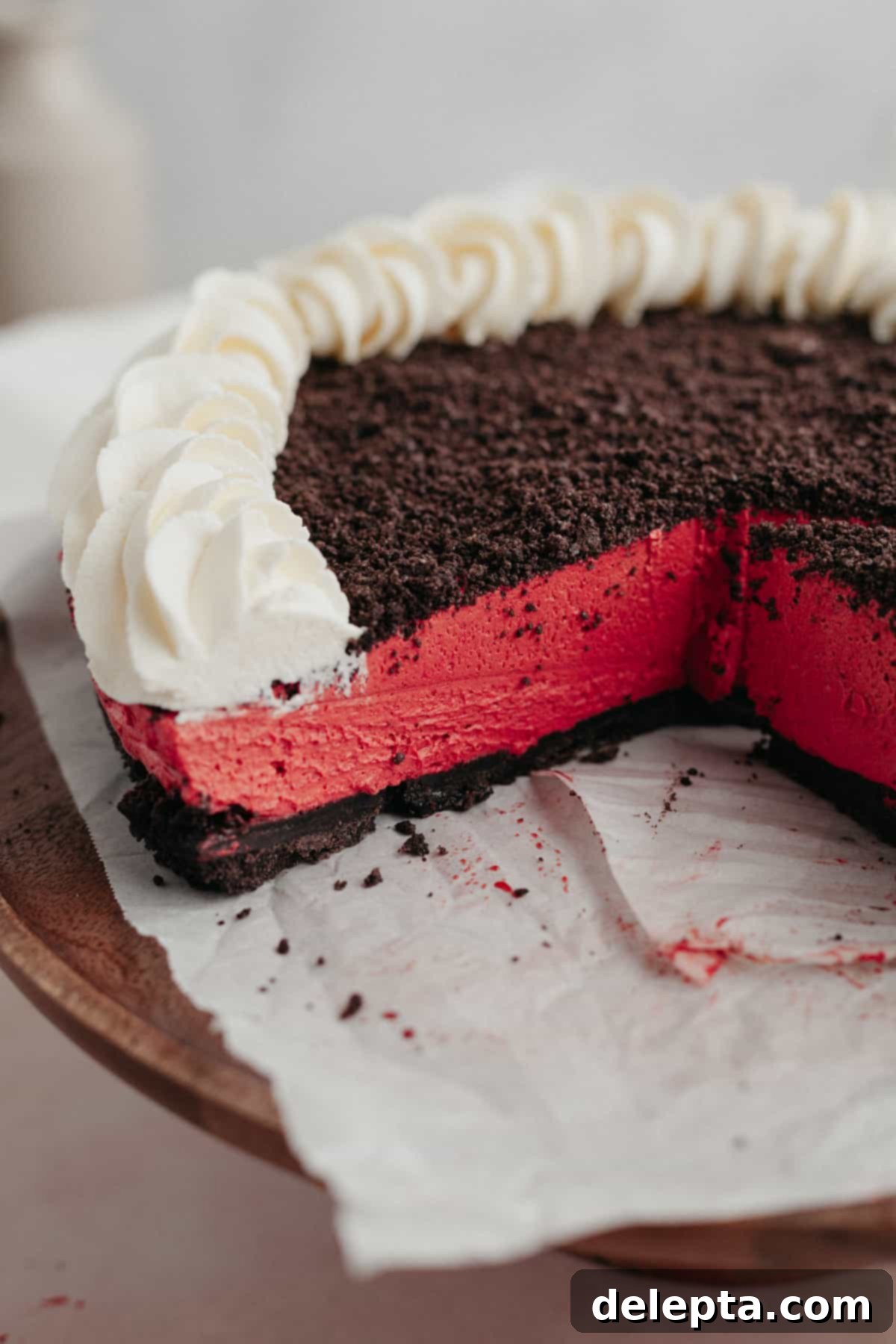 Decadent No-Bake Red Velvet Oreo Cheesecake 7 A close-up shot of a full Oreo red velvet cheesecake with a few slices already removed, showing the creamy texture and crust.