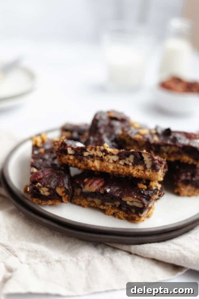 Decadent Chocolate Pecan Pie Bars 3 a small pile of freshly baked chocolate pecan pie bars on a white plate, ready to be enjoyed