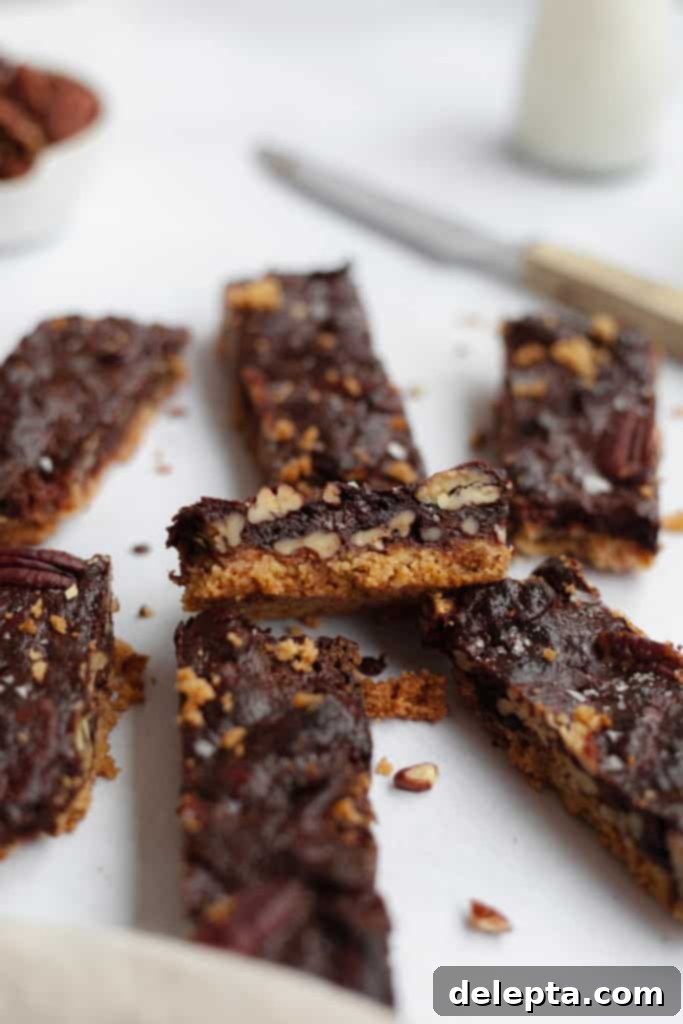 Decadent Chocolate Pecan Pie Bars 4 seven chocolate pecan pie bars arranged neatly on some parchment paper, highlighting their golden crust and rich, glossy filling