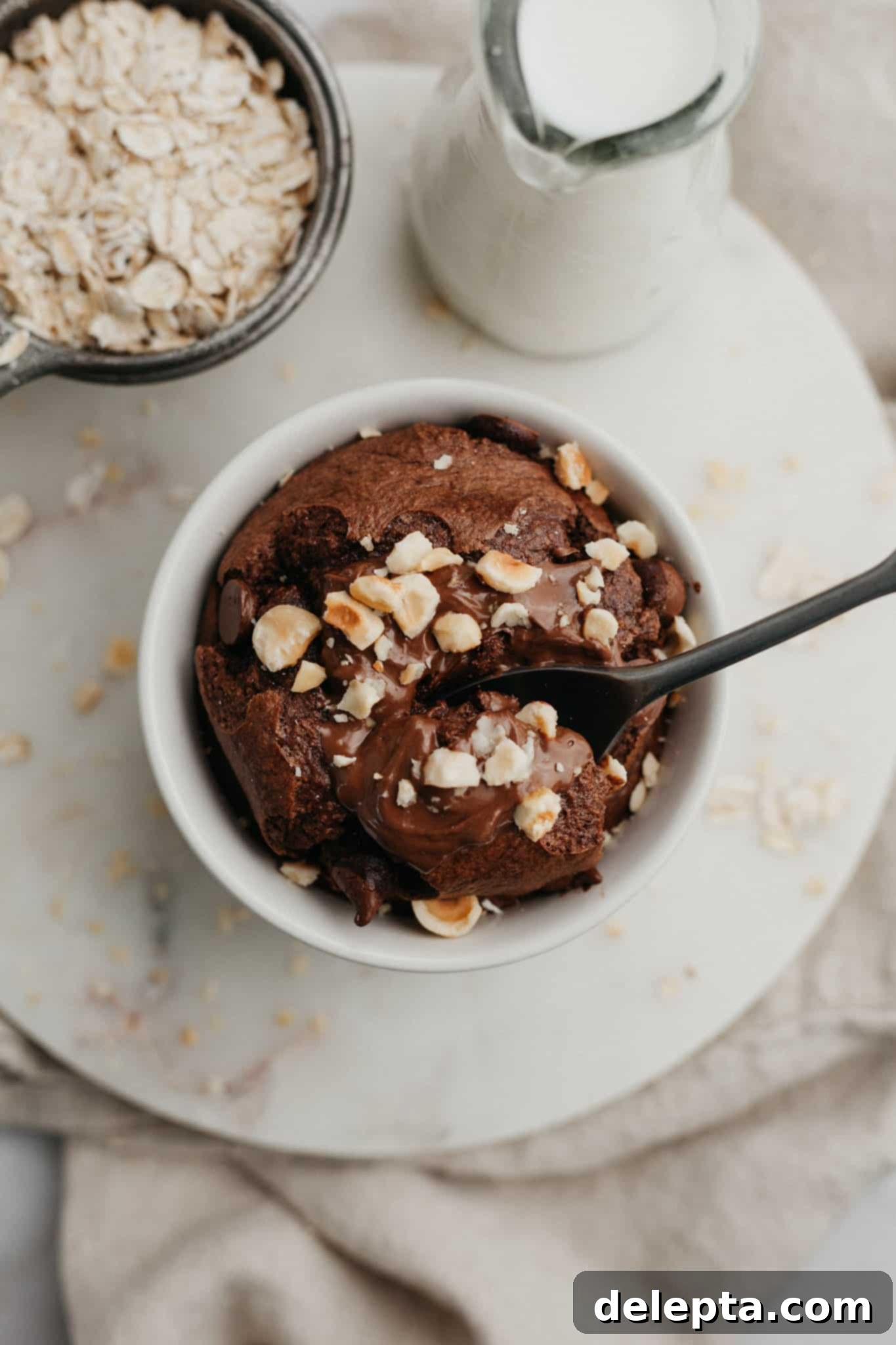 Decadent Nutella Baked Oats 2 An overhead shot of a small circular dish with rich, gooey Nutella baked oats, topped with chopped hazelnuts, ready to be enjoyed as a luxurious breakfast.