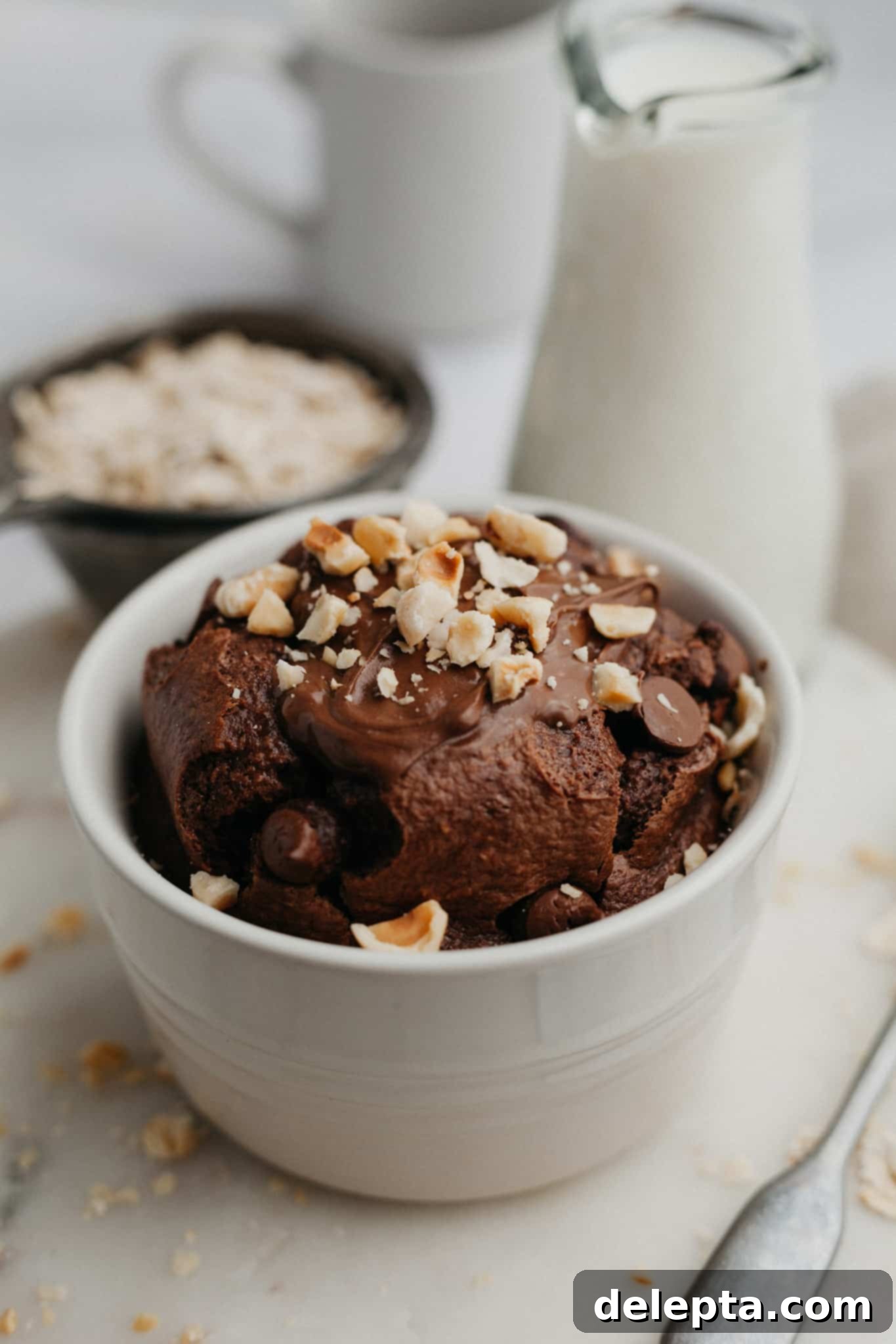 Decadent Nutella Baked Oats 5 A freshly baked dish of Nutella baked oats, topped with melted Nutella drizzle and a dusting of chopped hazelnuts, presented on a rustic wooden surface, ready for a delightful breakfast.