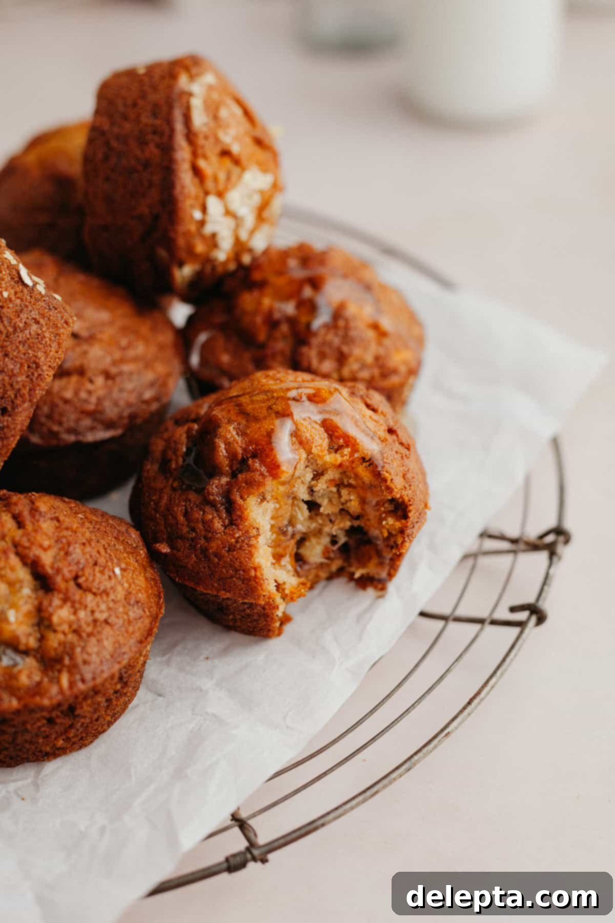 Sunshine Carrot Banana Muffins 2 Several muffins on parchment paper, one muffin has a bite taken out of it, revealing its moist, spiced interior.