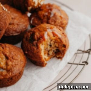 Sunshine Carrot Banana Muffins 8 Several muffins on parchment paper, one muffin has a bite taken out of it.