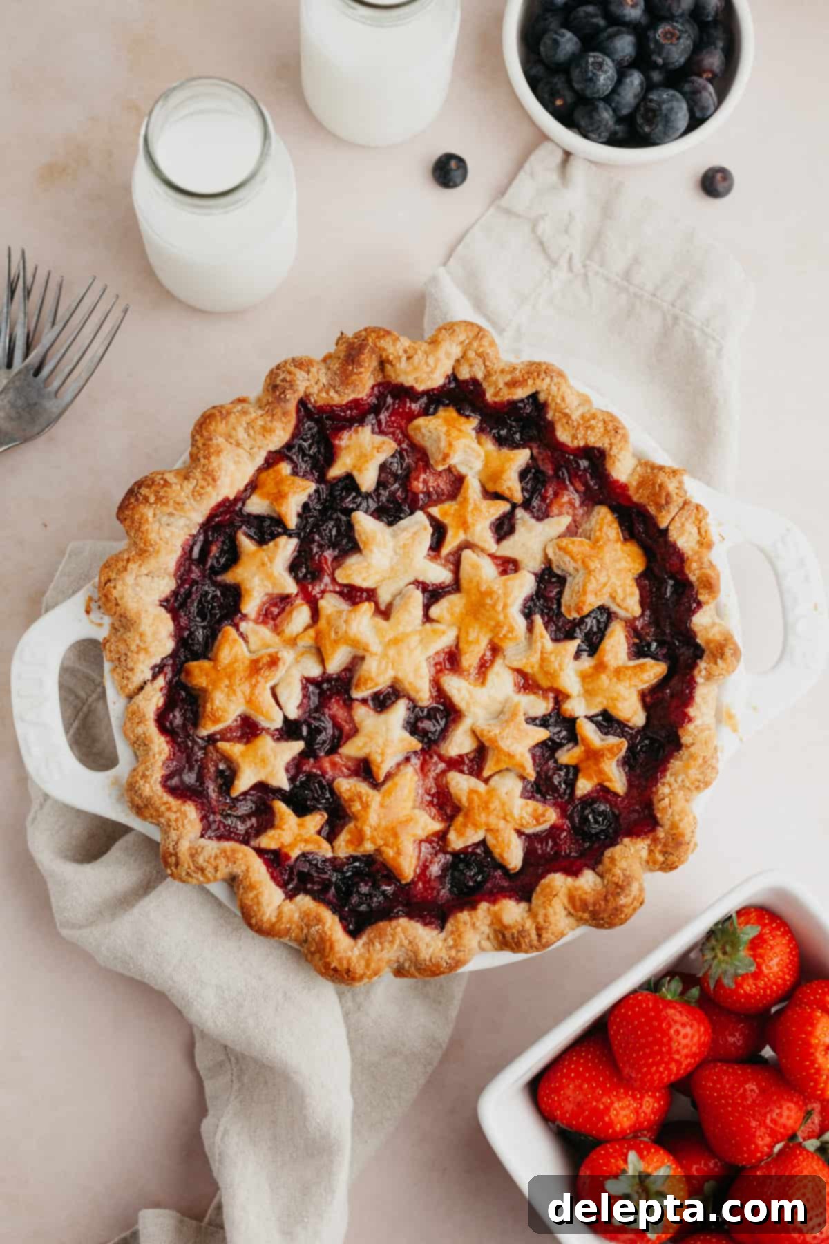 Double Berry Bliss Pie 2 A mixed berry pie covered in star pastry cutouts, glistening with a vibrant berry filling beneath.