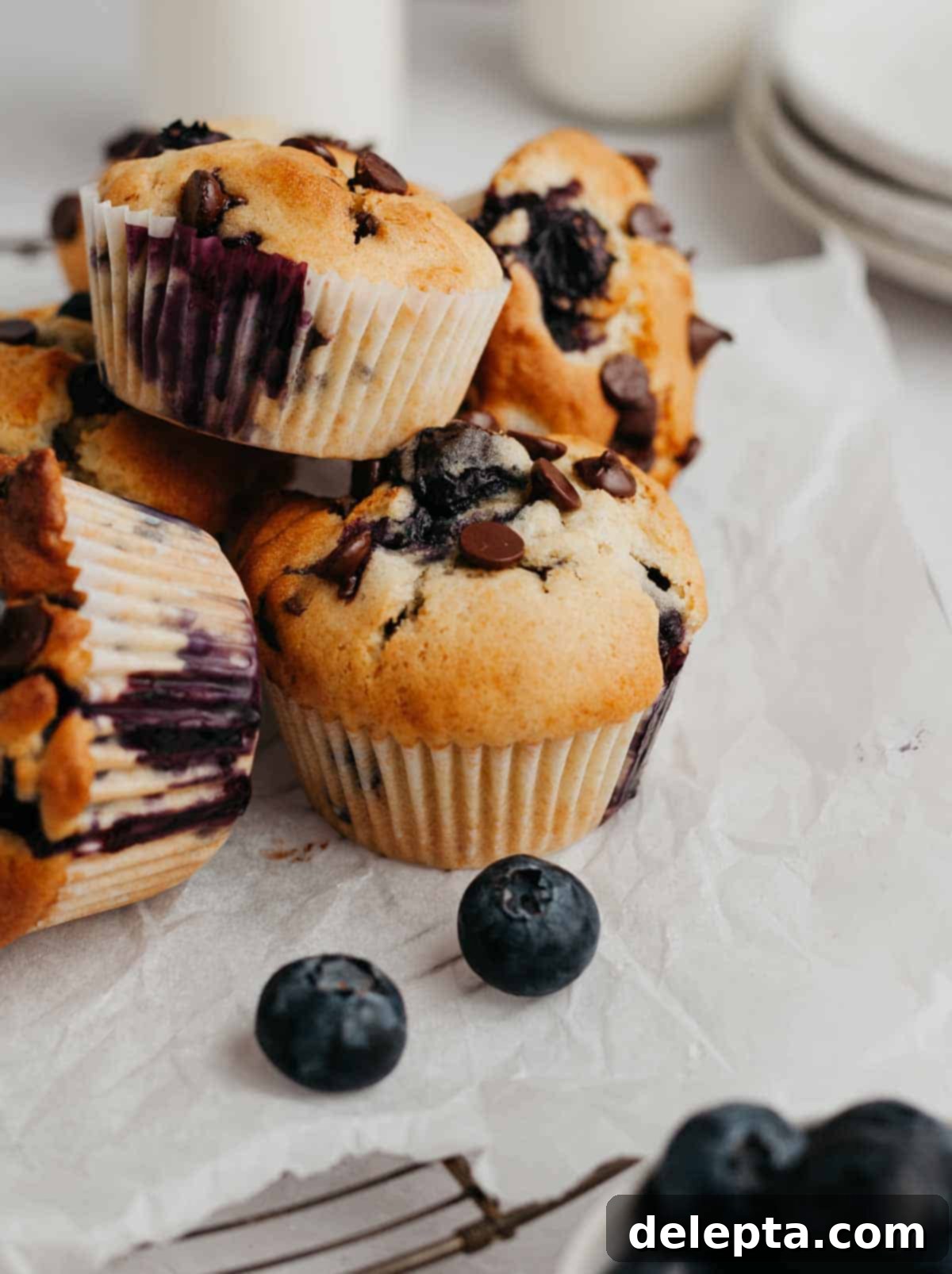 Ultimate Blueberry Chocolate Chip Muffins 7 Blueberry muffins with chocolate chips on parchment paper, ready to be enjoyed.