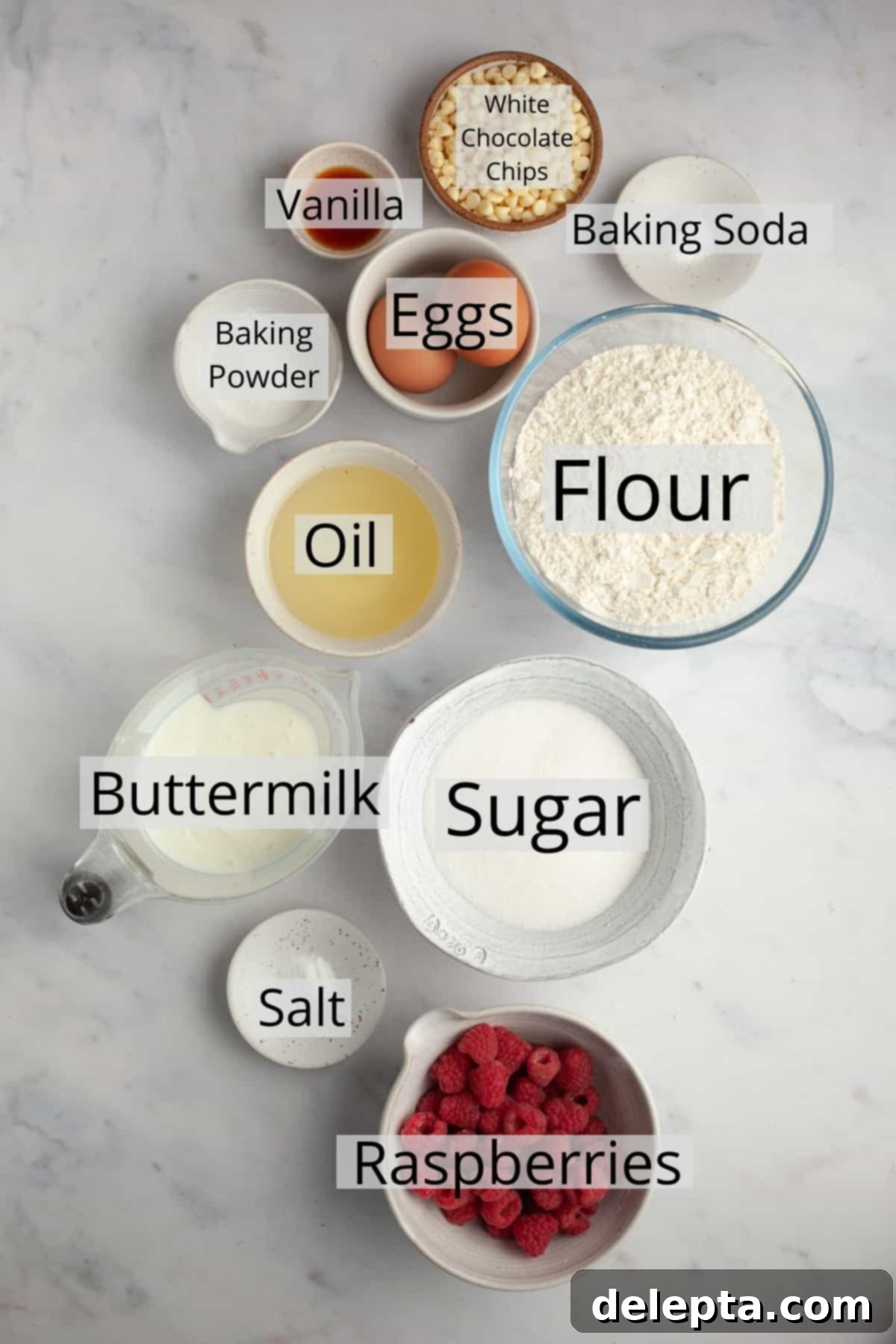 Decadent Raspberry White Chocolate Muffins 3 All the ingredients needed to make raspberry white chocolate muffins laid out in small bowls, ready for baking.