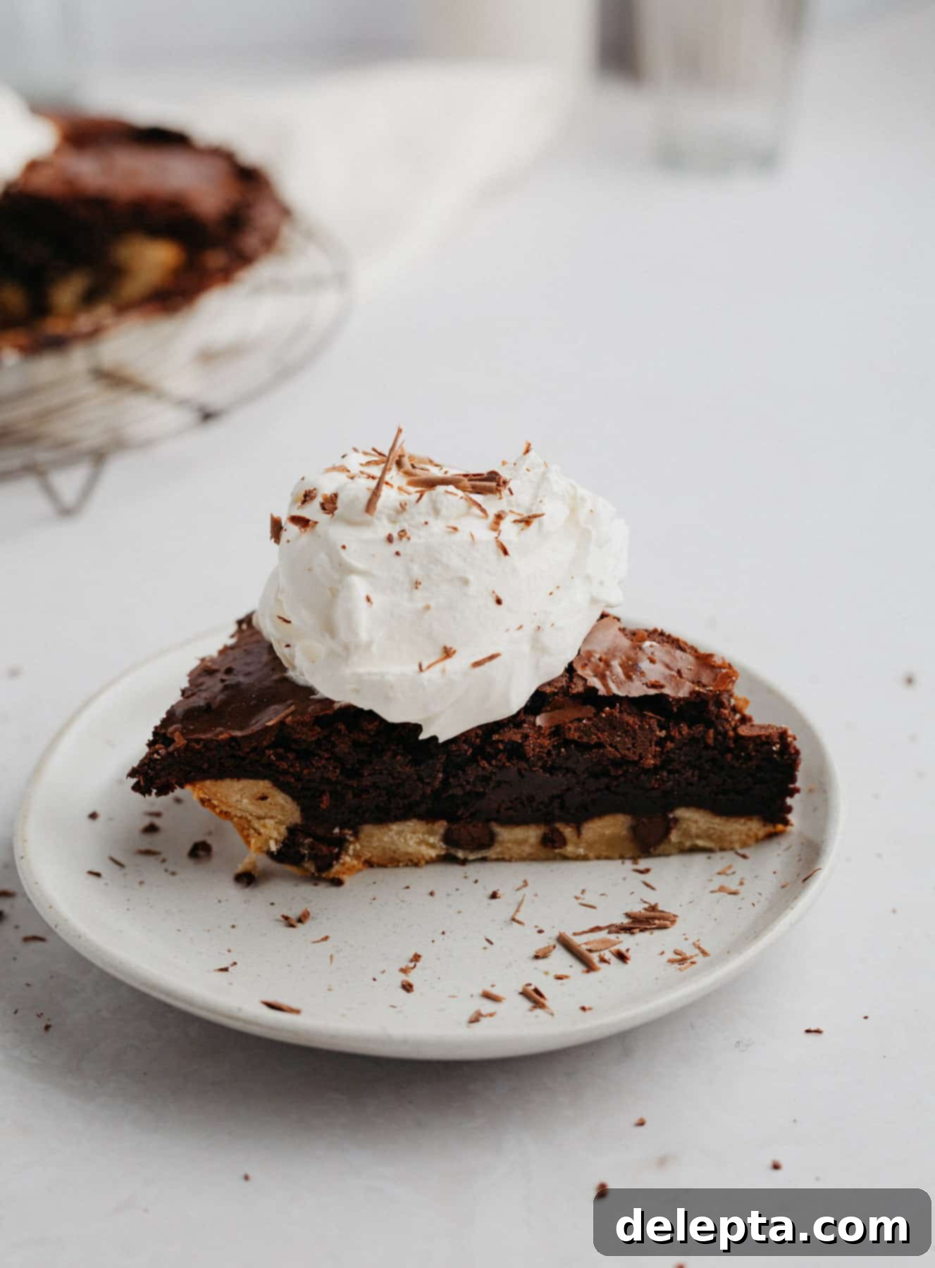 Fudgy Brownie Pie 2 A perfectly sliced brownie pie, or brookie pie, with a dollop of homemade whipped cream on top, showcasing its incredibly fudgy interior and distinct chewy chocolate chip cookie crust layers.