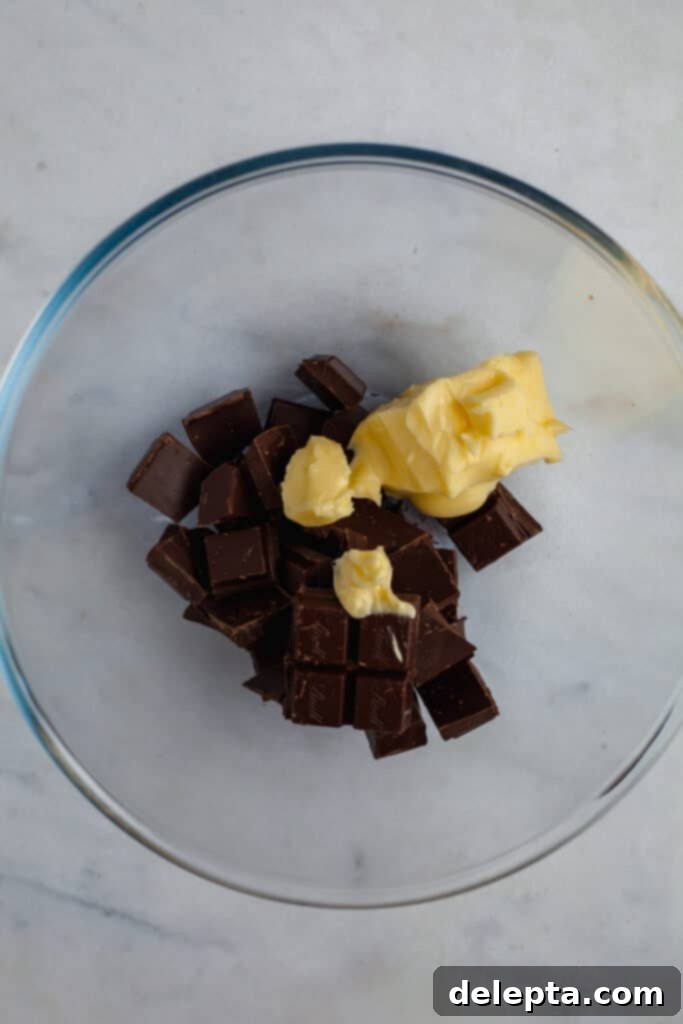 Fudgy Brownie Pie 12 Generous chunks of chopped dark chocolate and softened butter melting together in a heatproof bowl positioned over a double boiler, creating a luxurious, smooth, and glossy mixture.