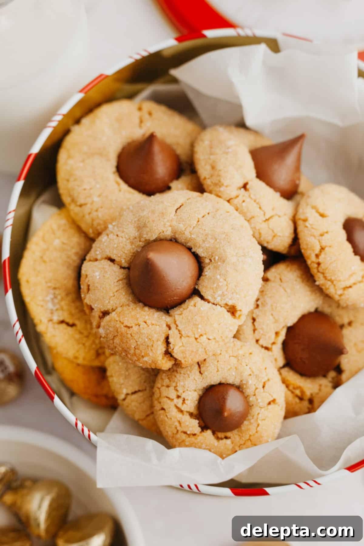 Beloved Hershey's Kiss Thumbprint Cookies 2 A pile of freshly baked peanut butter thumbprint cookies, each topped with a melted Hershey's Kiss, nestled in a festive tin.