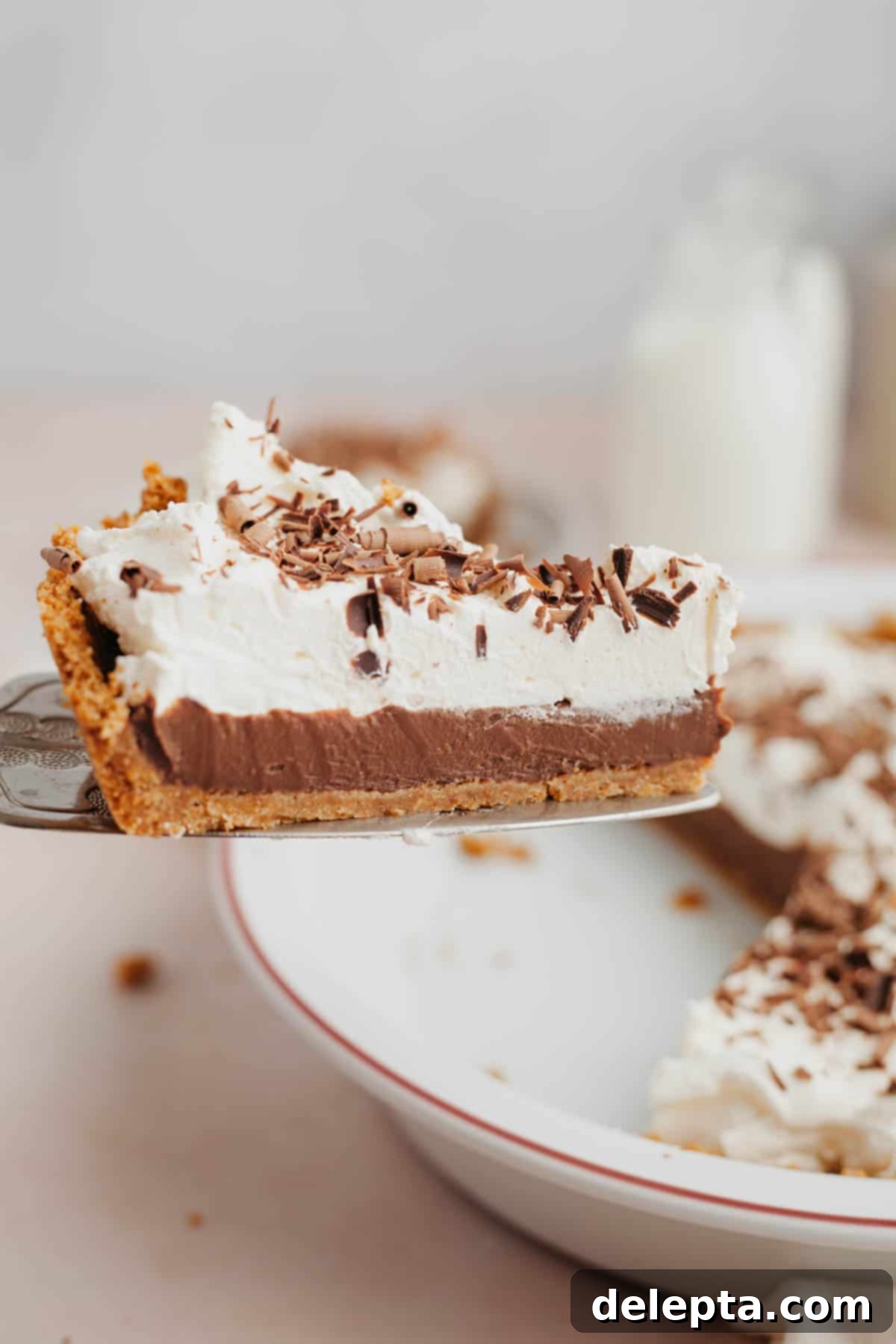 No-Bake Chocolate Pudding Pie with Buttery Graham Crust 2 A slice of chocolate and whipped cream pie being lifted out with a silver server.