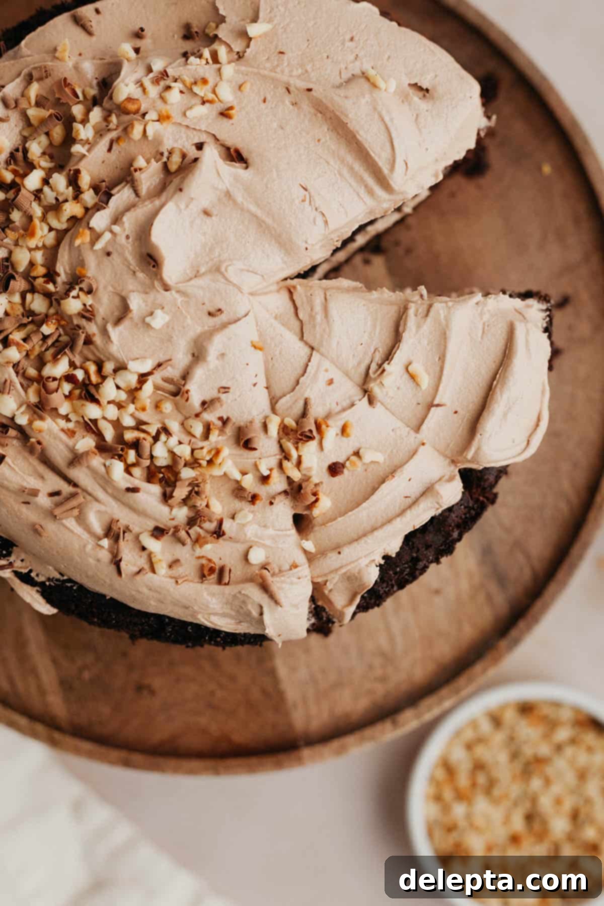 Decadent Nutella Delight 8 An inviting overhead shot of a beautifully frosted Nutella chocolate cake, adorned with chopped hazelnuts, with several slices already cut and ready to serve.