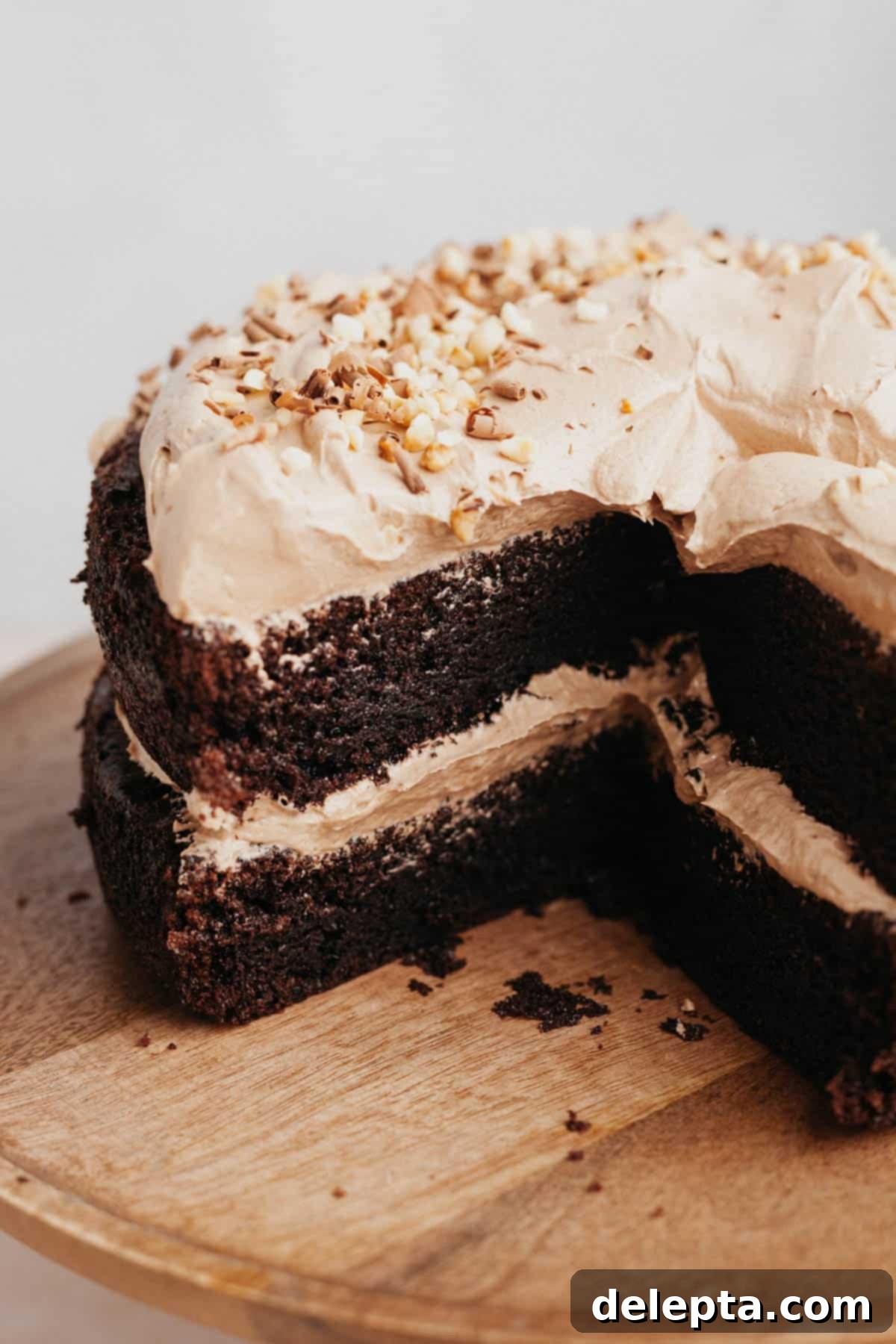 Decadent Nutella Delight 9 A stunning two-layer chocolate Nutella cake, expertly cut to reveal its moist interior, beautifully displayed on a rustic wooden cake stand.