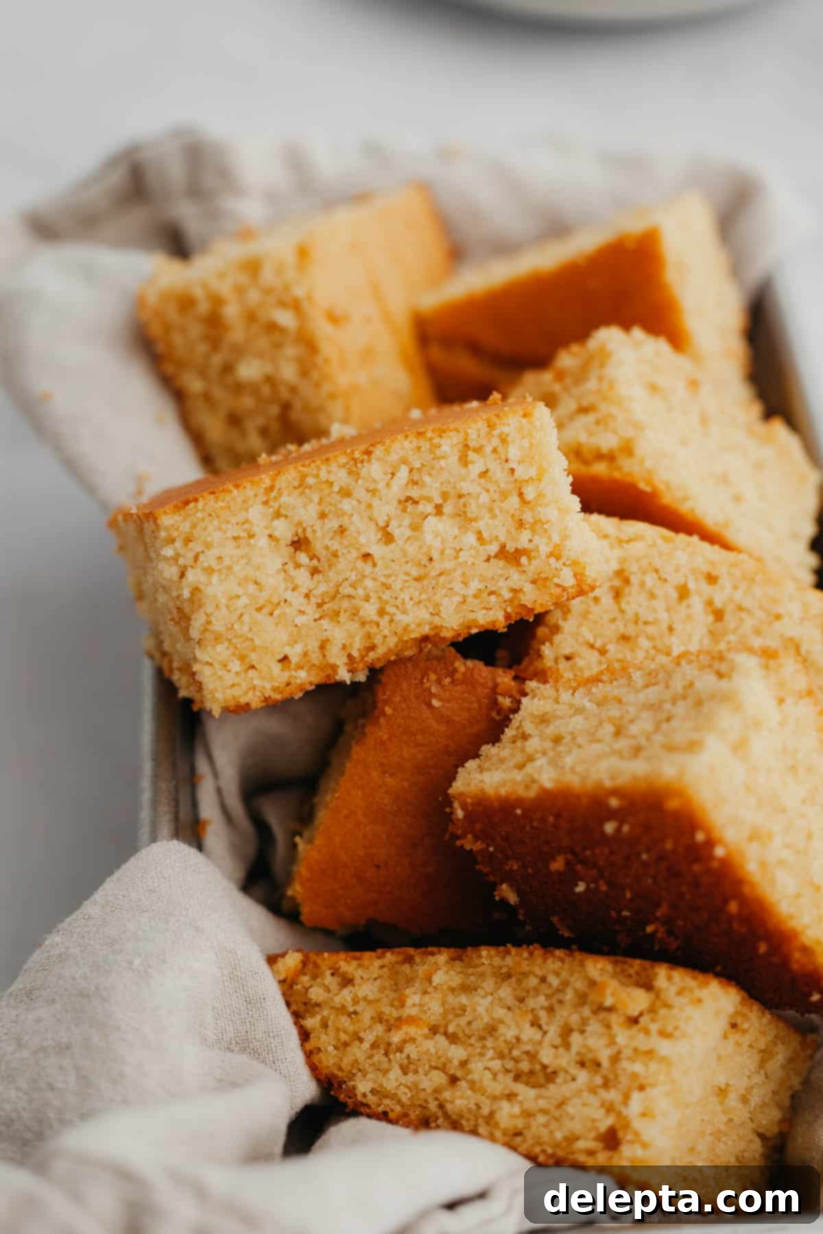 Pantry Staple Cornbread 7 A slice of warm, moist cornbread on a plate, ready to be served
