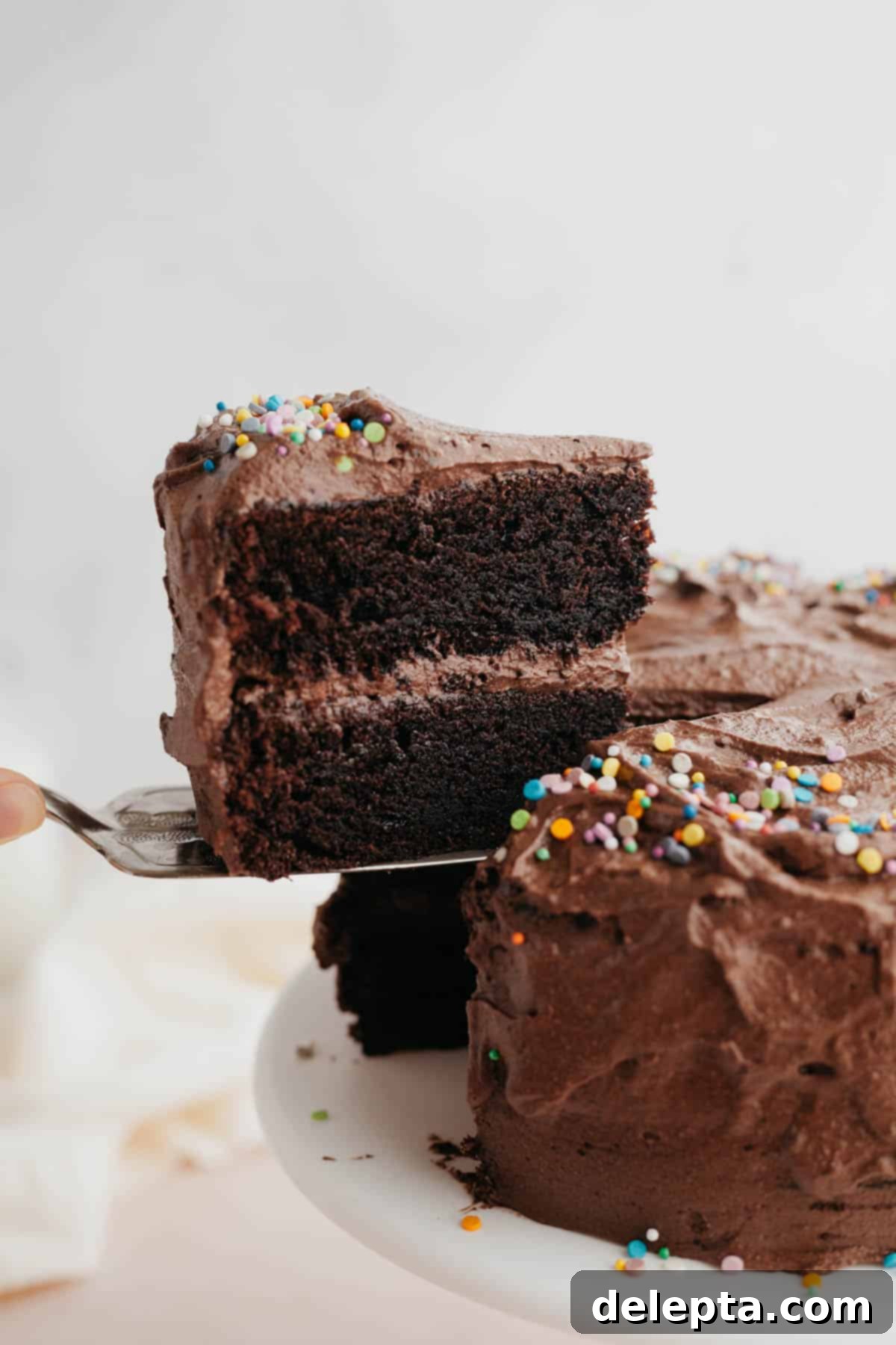 Velvet Chocolate Cream Cheese Delight 2 A perfectly sliced piece of moist chocolate cake being lifted out with a silver server, showcasing the rich layers and creamy frosting.