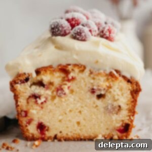 Lemon-Kissed Cranberry Loaf with White Chocolate Embrace 12 A festive cranberry lemon bread loaf, beautifully cut to display its moist interior and vibrant cranberries, crowned with creamy white chocolate frosting and sparkling sugared cranberries.