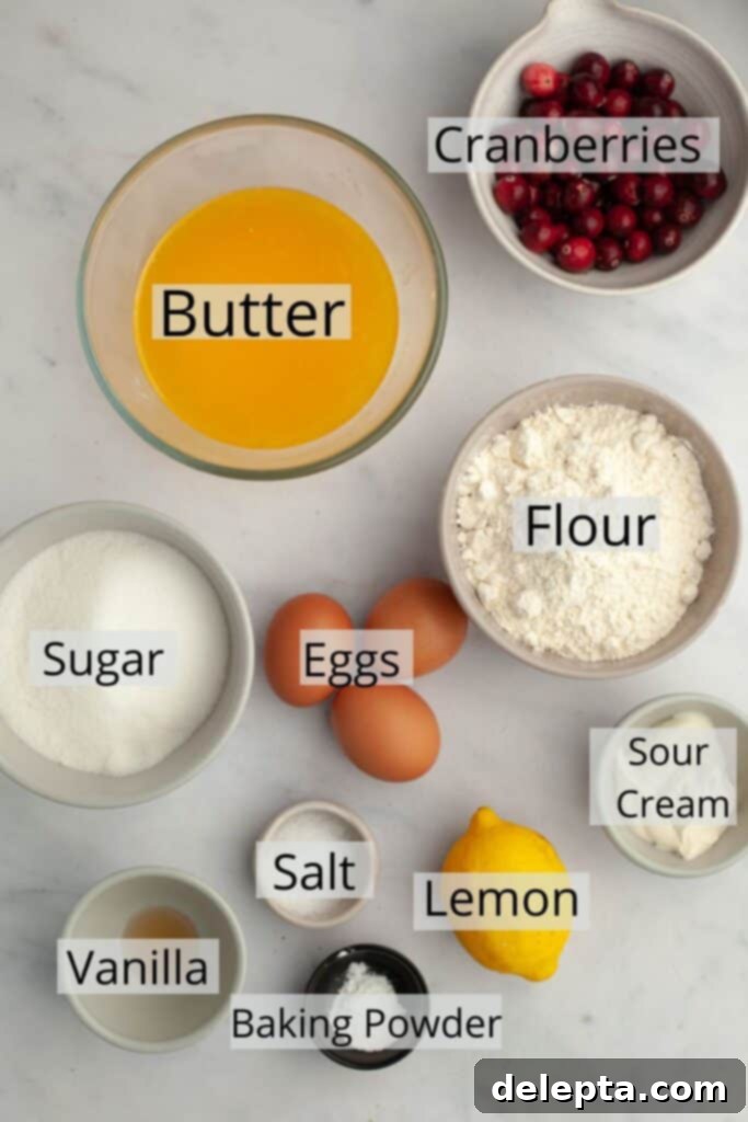 Lemon-Kissed Cranberry Loaf with White Chocolate Embrace 3 A selection of pre-measured ingredients for cranberry lemon bread, including flour, sugar, eggs, butter, sour cream, vanilla, lemon zest, and fresh cranberries, neatly arranged in small white bowls.