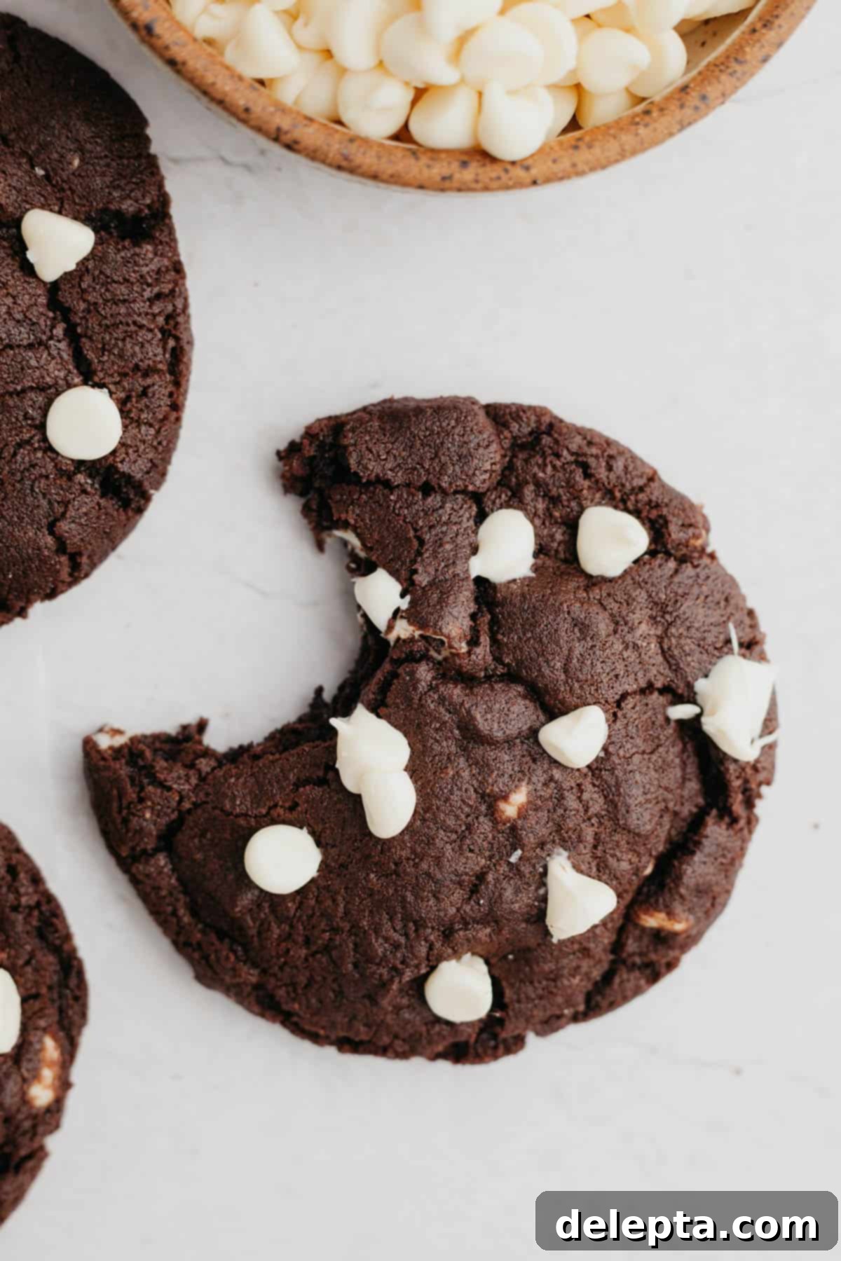 Chocolate Chip Showcase Cookies 7 A chocolate cookie with white chocolate chips with a bite taken out of it.