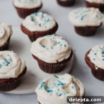 Hanukkah's Golden Glow: Chocolate, Salted Caramel & Tahini Buttercream Cupcakes 6 Ten Hanukkah chocolate cupcakes generously frosted with light tahini buttercream and adorned with festive blue and white sprinkles, arranged on a rustic wooden surface