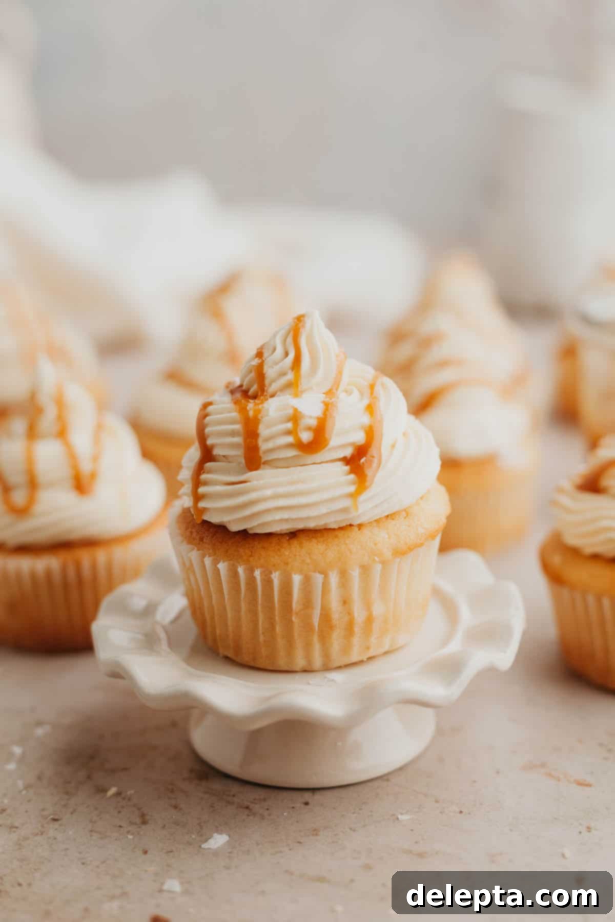 Caramel Burst Cupcakes 2 Caramel filled cupcakes, the one at the front is on a small cupcake stand.