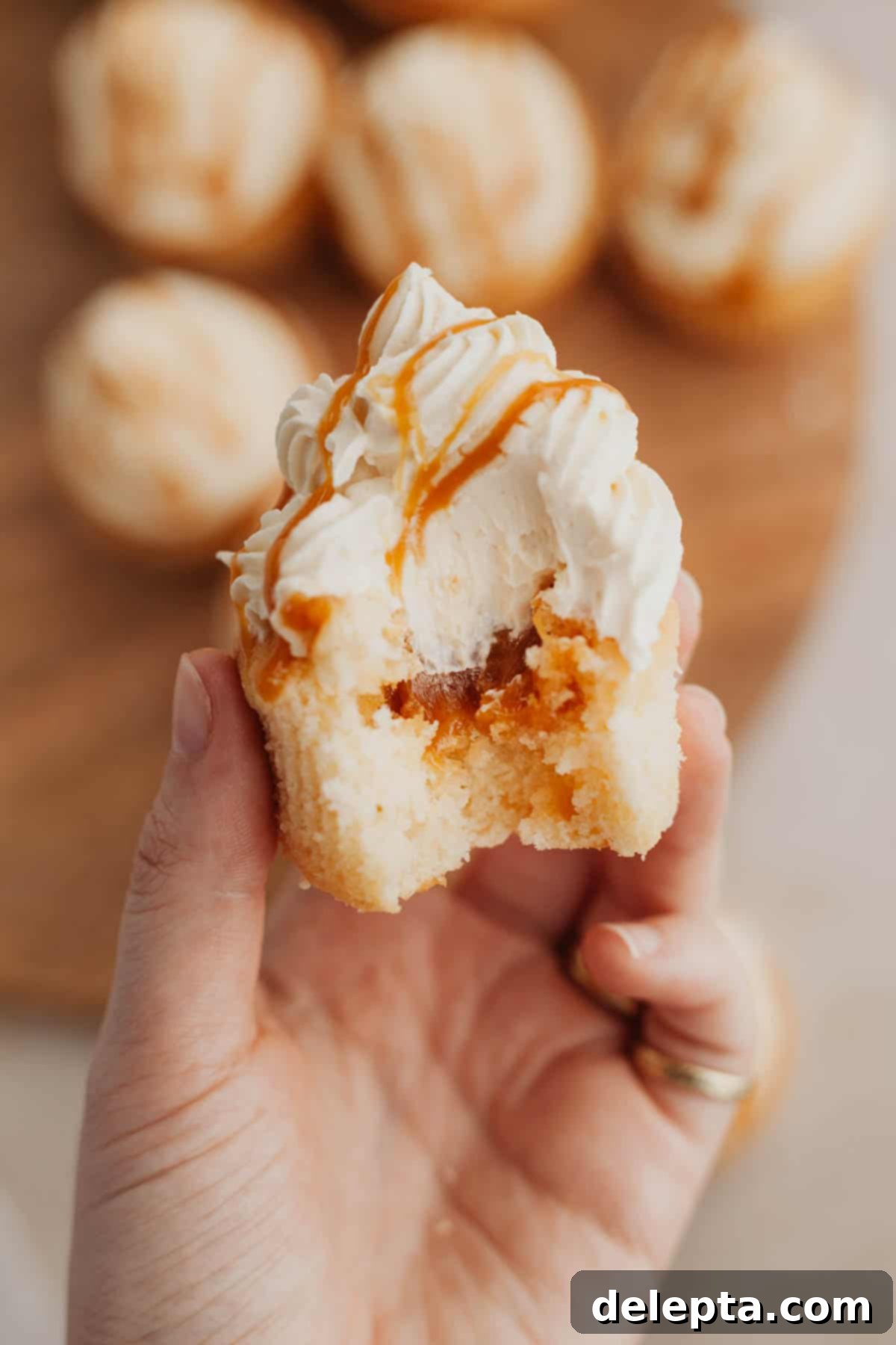 Caramel Burst Cupcakes 12 A hand holding a caramel filled cupcake.