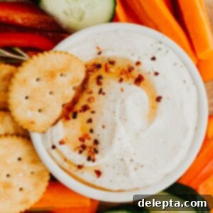Sweet Heat Ricotta Cloud 7 A white bowl filled with whipped ricotta dip and drizzled with hot honey, it is surrounded by cut up vegetables.
