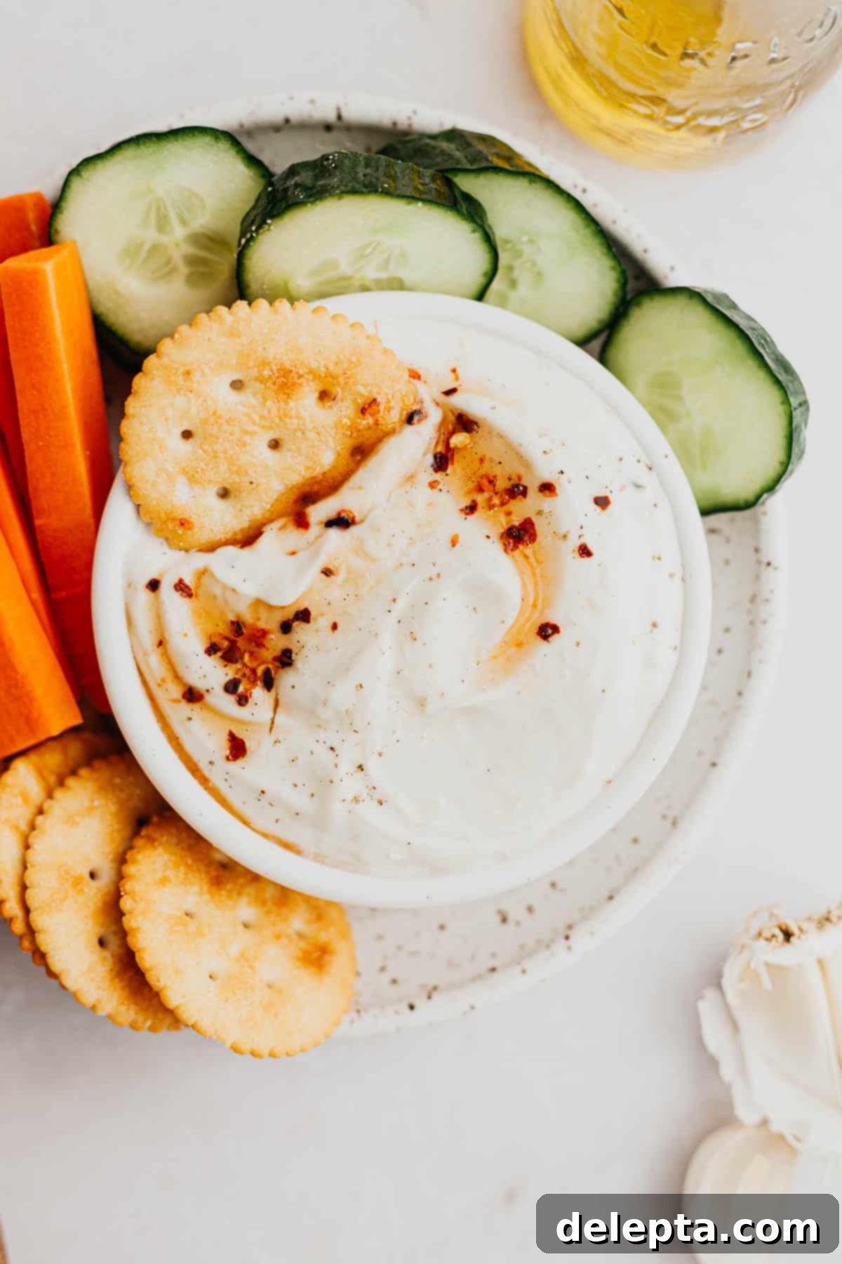 Sweet Heat Ricotta Cloud 6 A beautifully composed overhead shot of a white bowl filled with creamy whipped ricotta dip, artfully garnished with a generous drizzle of golden hot honey, a sprinkle of vibrant red chili flakes, and delicate fresh rosemary sprigs. The dip is elegantly surrounded by a vibrant arrangement of crisp, colorful cut vegetables and crunchy crackers, creating an inviting and visually appealing appetizer spread.