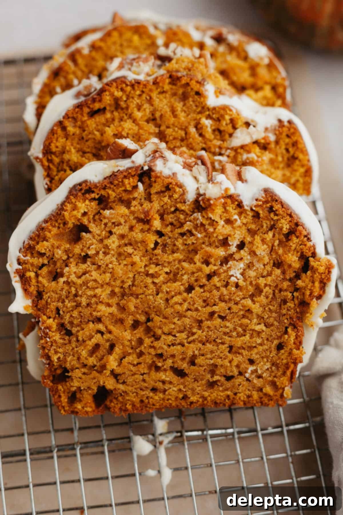 Velvet Pumpkin Loaf with Rich Cream Cheese Frosting 8 Three perfectly sliced pieces of pumpkin bread cooling on a wire rack, showcasing its moist texture.