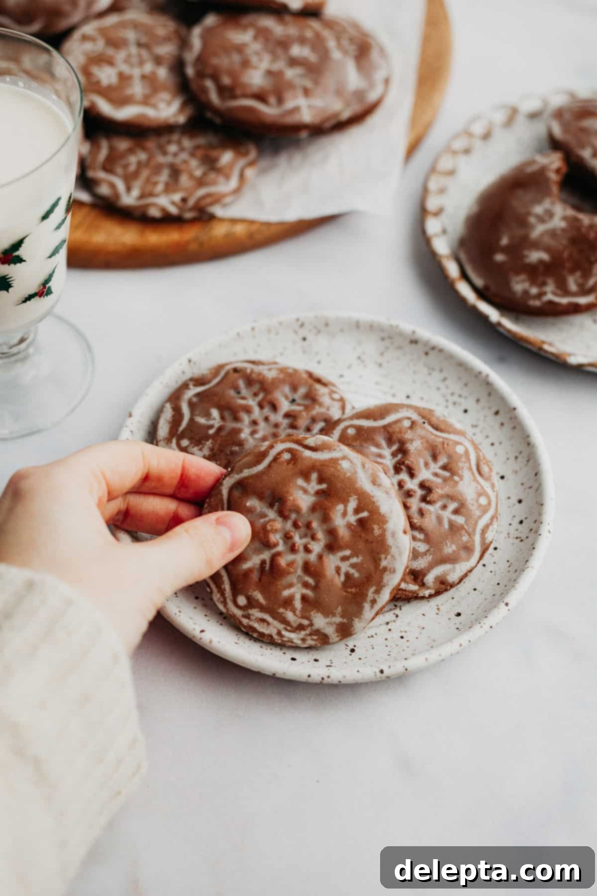 Old World German Gingerbread 2 A pile of beautifully stamped and glazed gingerbread cookies, a woman's hand is delicately holding one, showcasing its snowflake design.