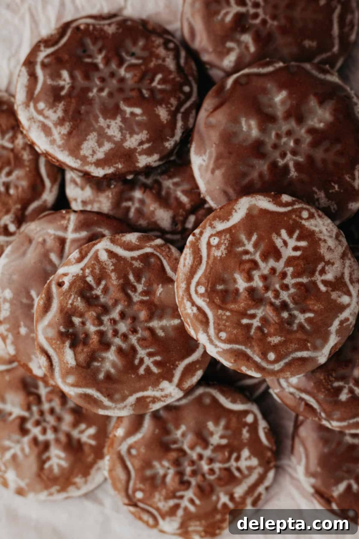 Old World German Gingerbread 8 A beautifully arranged pile of dark chocolate gingerbread cookies, each adorned with a distinct snowflake stamp.
