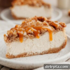 Apple Crumble Cheesecake 12 A slice of apple crisp cheesecake drizzled in salted caramel sauce on a small beige plate, garnished for serving.