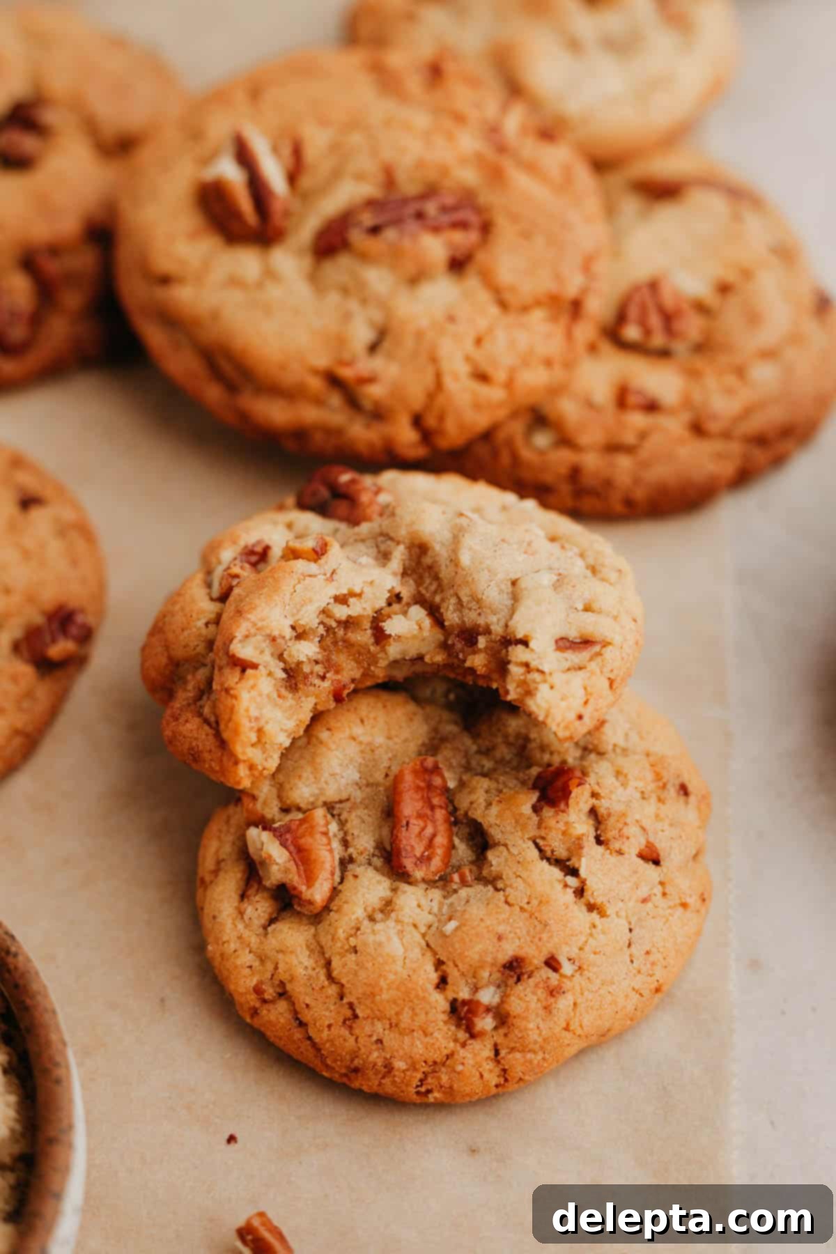 Toasted Butter Pecan Gems 8 Two browned butter pecan cookies stacked on top of each other, one with a delicious bite taken out.