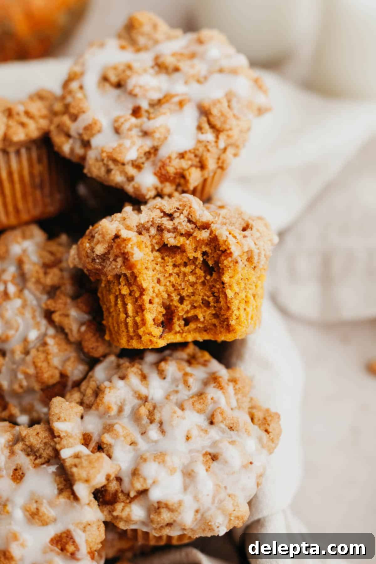 Autumn Spiced Pumpkin Crumble Muffins 2 A close up of a pumpkin muffin with a streusel topping, a bite has been taken out of it.