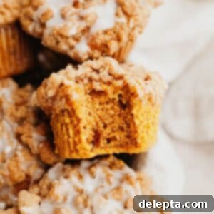 Autumn Spiced Pumpkin Crumble Muffins 9 A close up of a pumpkin muffin with a streusel topping, a bite has been taken out of it.