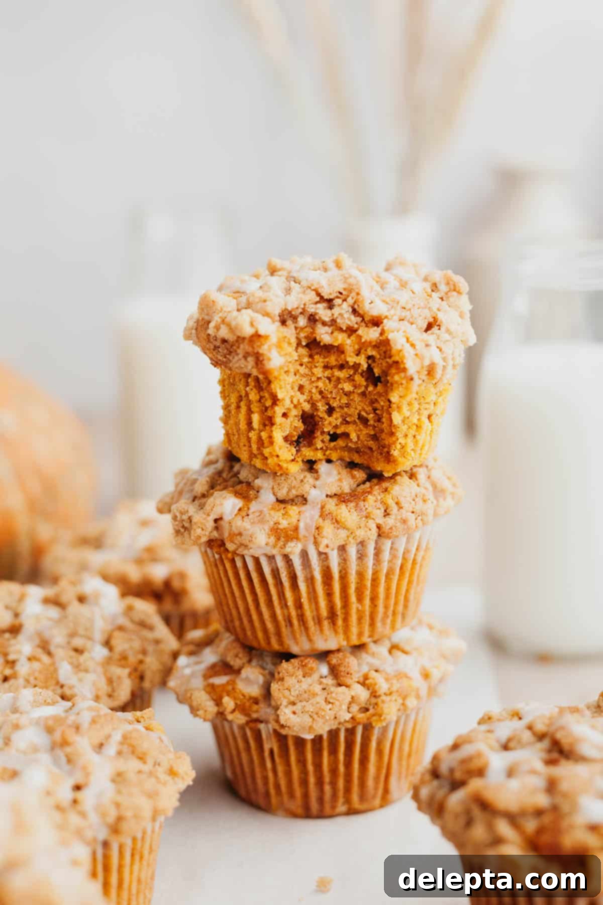 Autumn Spiced Pumpkin Crumble Muffins 8 A stack of three pumpkin muffins with a streusel topping.