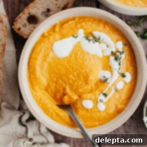 Velvet Pumpkin Carrot Soup 9 A white bowl with pumpkin carrot soup in it, drizzled with heavy cream and thyme.