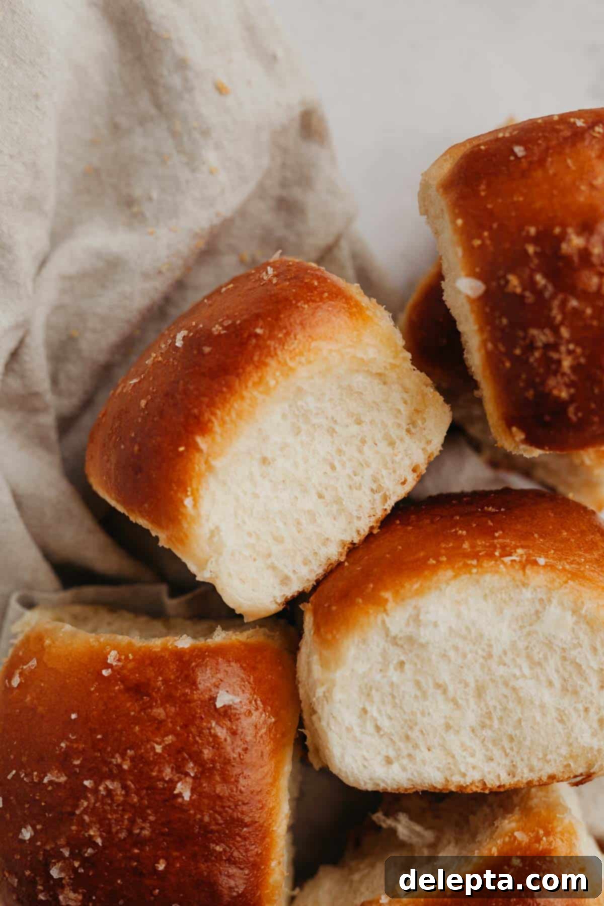 Soft Brioche Dinner Rolls 2 Four brioche dinner rolls on a beige linen.