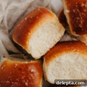 Soft Brioche Dinner Rolls 9 Four brioche dinner rolls on a beige linen.