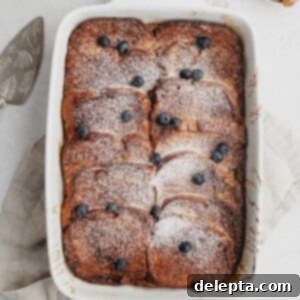 Decadent Brioche French Toast Bake 8 Baked brioche french toast in a white casserole dish, it has powdered sugar on it.