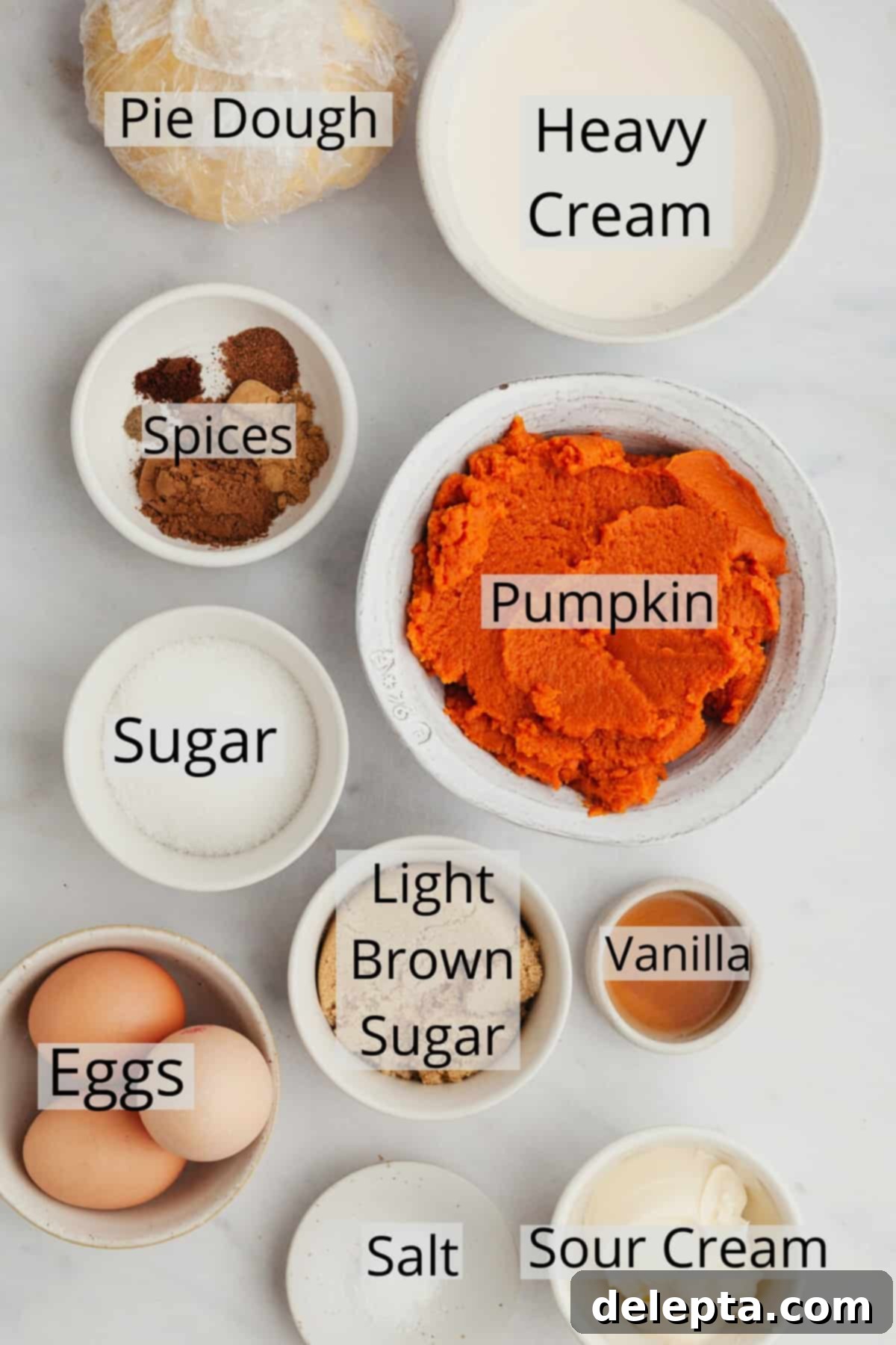Creamy Pumpkin Dream Pie 3 A collection of measured ingredients laid out in small bowls, including pumpkin puree, spices, and dairy, ready for making a pumpkin pie.