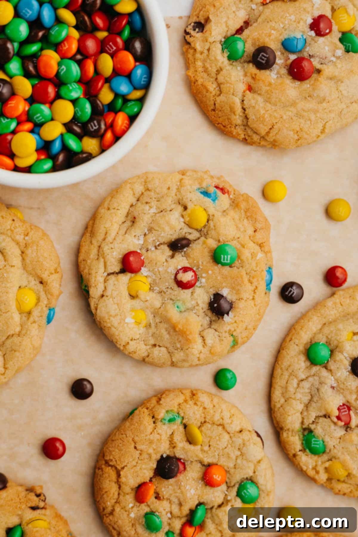 Pillowy M&M Cookie Bites 8 A close-up of rainbow mini M&M cookies, perfectly round and vibrant, arranged on parchment paper on a baking sheet.