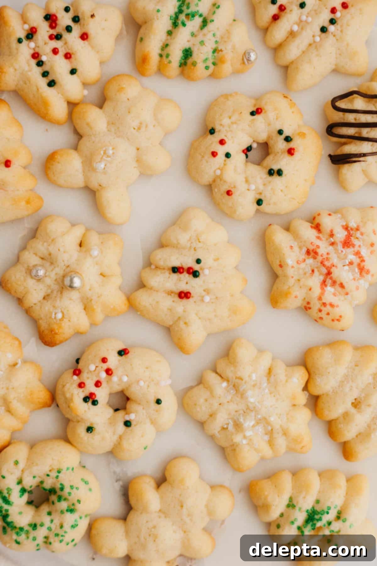 Velvet Cream Cheese Spritz Delights 2 Festive cream cheese spritz cookies decorated with colorful sprinkles, arranged on a marble surface.