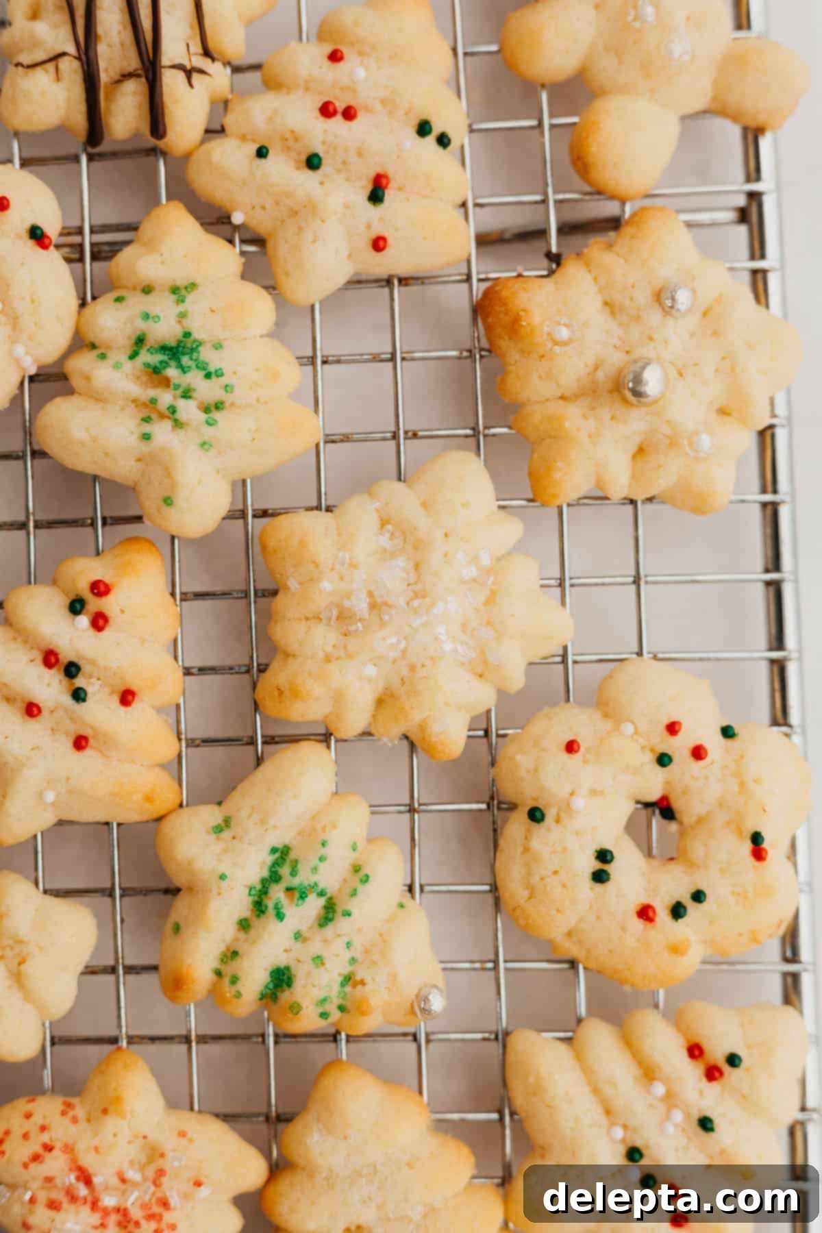 Velvet Cream Cheese Spritz Delights 6 Freshly baked Christmas cream cheese spritz cookies cooling on a wire rack.