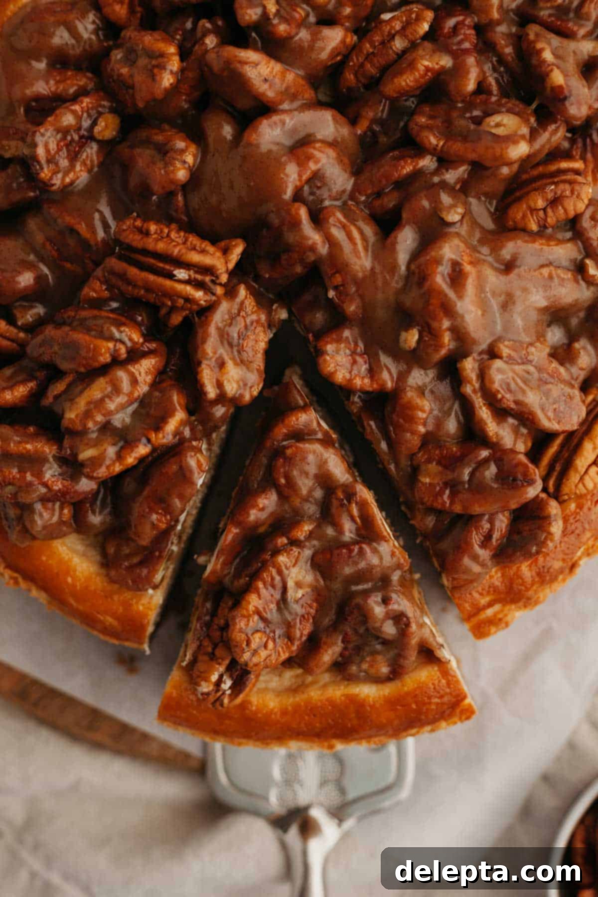 Decadent Pecan Pie Cheesecake 8 An inviting overhead shot of a whole pecan pie cheesecake with a single slice removed, revealing its beautiful layers.