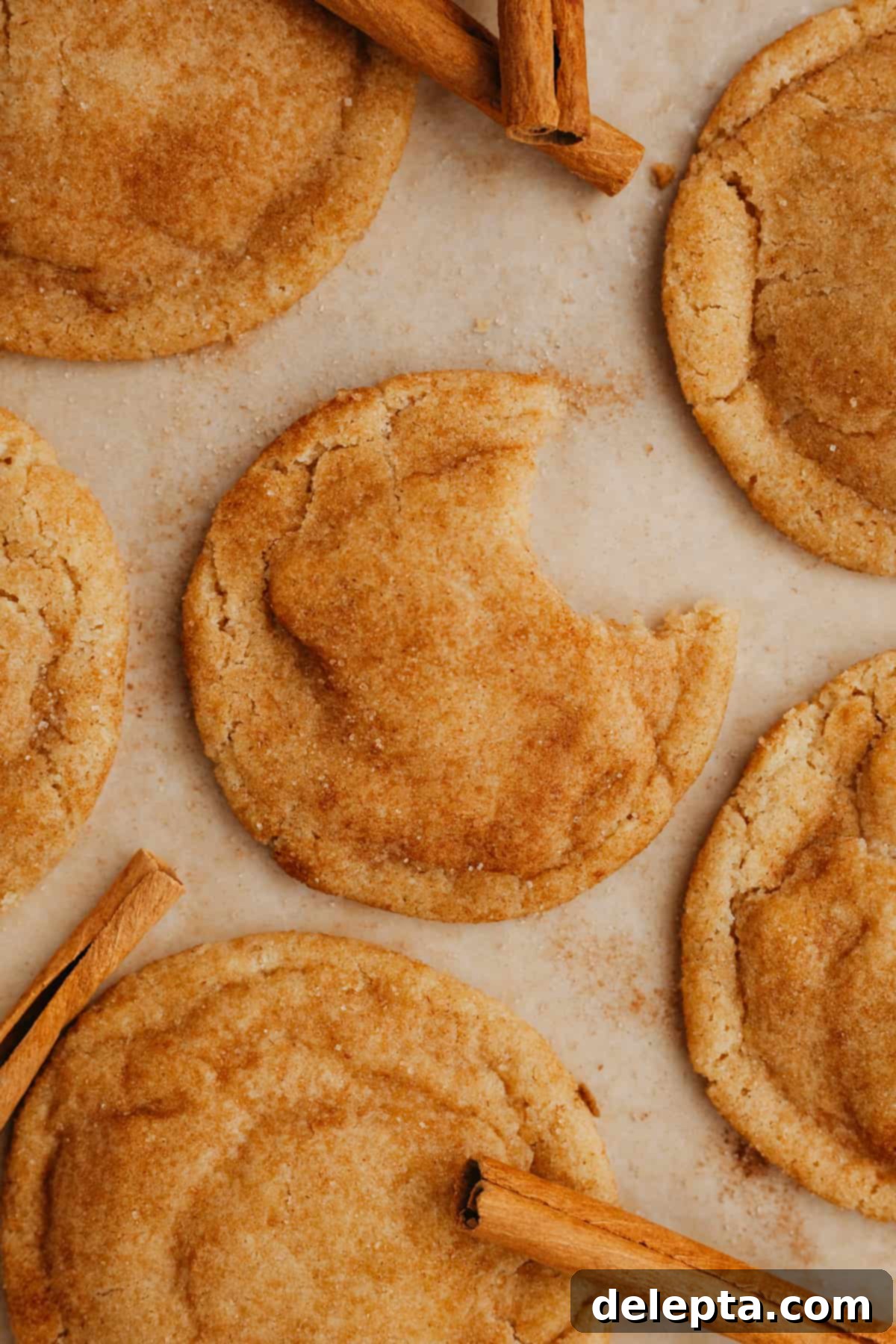 Nutty Brown Butter Snickerdoodles 7 Freshly baked snickerdoodle cookies cooling on parchment paper after being removed from the oven, showing their characteristic crinkled tops.
