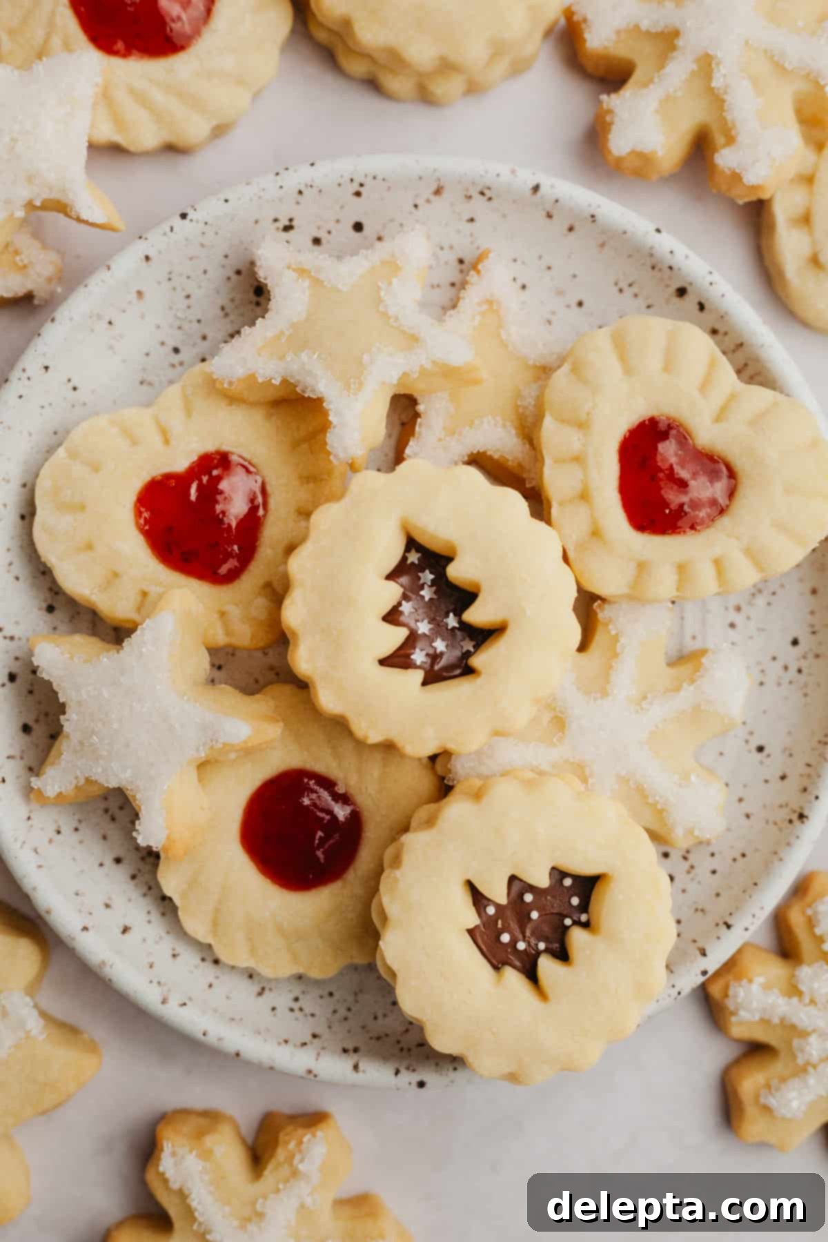 Foolproof Cutout Shortbread Cookies 2 A small plate showcasing beautifully decorated cutout shortbread cookies in various holiday shapes like stars and snowflakes, ready for a festive celebration.