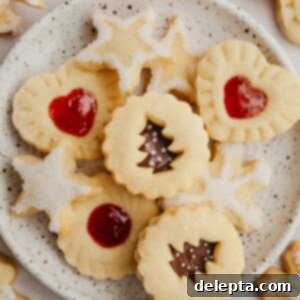 Foolproof Cutout Shortbread Cookies 9 A small plate showcasing beautifully decorated cutout shortbread cookies in various holiday shapes like stars and snowflakes.