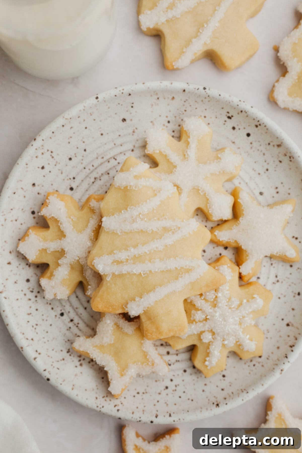 Foolproof Cutout Shortbread Cookies 6 A charming plate filled with festive cut-out shortbread cookies, shaped as delicate snowflakes, classic Christmas trees, and radiant stars.