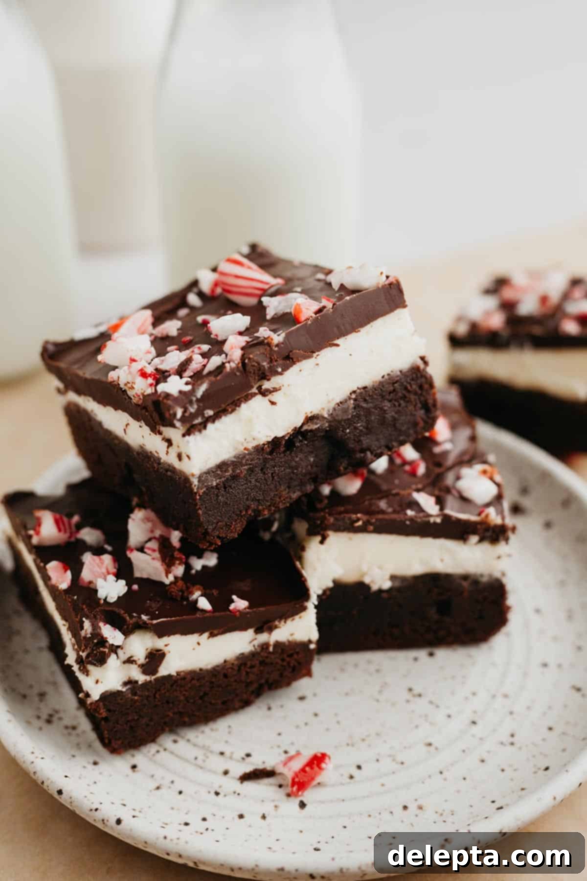 Peppermint Bark Fudge Squares 10 A stack of delightful layered peppermint bark brownies resting on a small, elegant plate, showcasing their festive appeal.