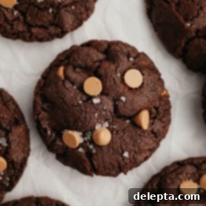 Decadent Caramel Chocolate Cookies 9 A close-up of a perfectly baked chocolate caramel cookie on parchment paper, ready to be enjoyed.